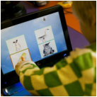 Foto van een hand van een jong kind dat wijs op een computerscherm waarop vier foto's van dieren te zien zijn.