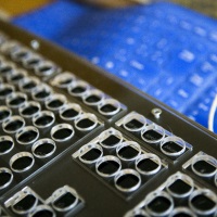 Foto van een zwart toetsenbord met plexiglas rooster en blauw flexibel toetsenbord op de achtergrond