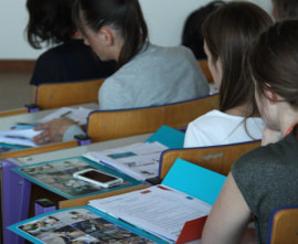 Foto van enkele personen in een klas met opengeslagen mapjes