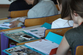 Foto van enkele personen in een klas met opengeslagen mapjes