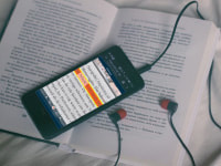 Foto van een boek waarop een smartphone ligt. Op het scherm van de smartphone staat tekst waarvan 1 regel oranje is gemarkeerd.